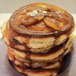 Stacked pancakes topped with cinnamon apples and cinnamon butter syrup