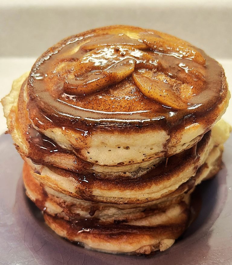 Stacked pancakes topped with cinnamon apples and cinnamon butter syrup
