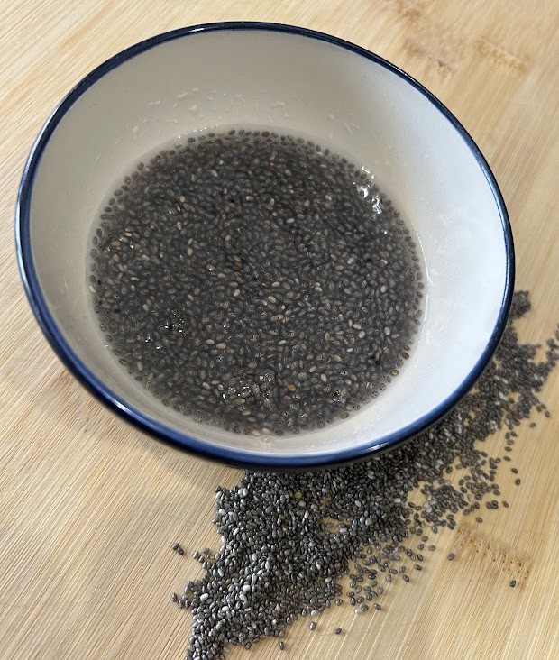Chia eggs on a brown cutting board and in a small bowl of water