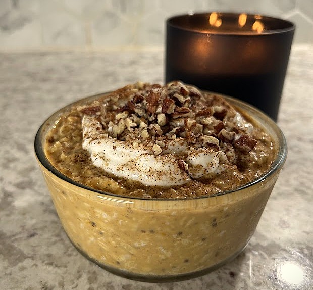 Pumpkin pie overnight oats on a granite countertop next to a black candle.