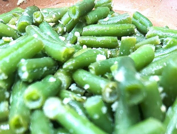 A close up image of Garlic green beans on a brown sauté pan.