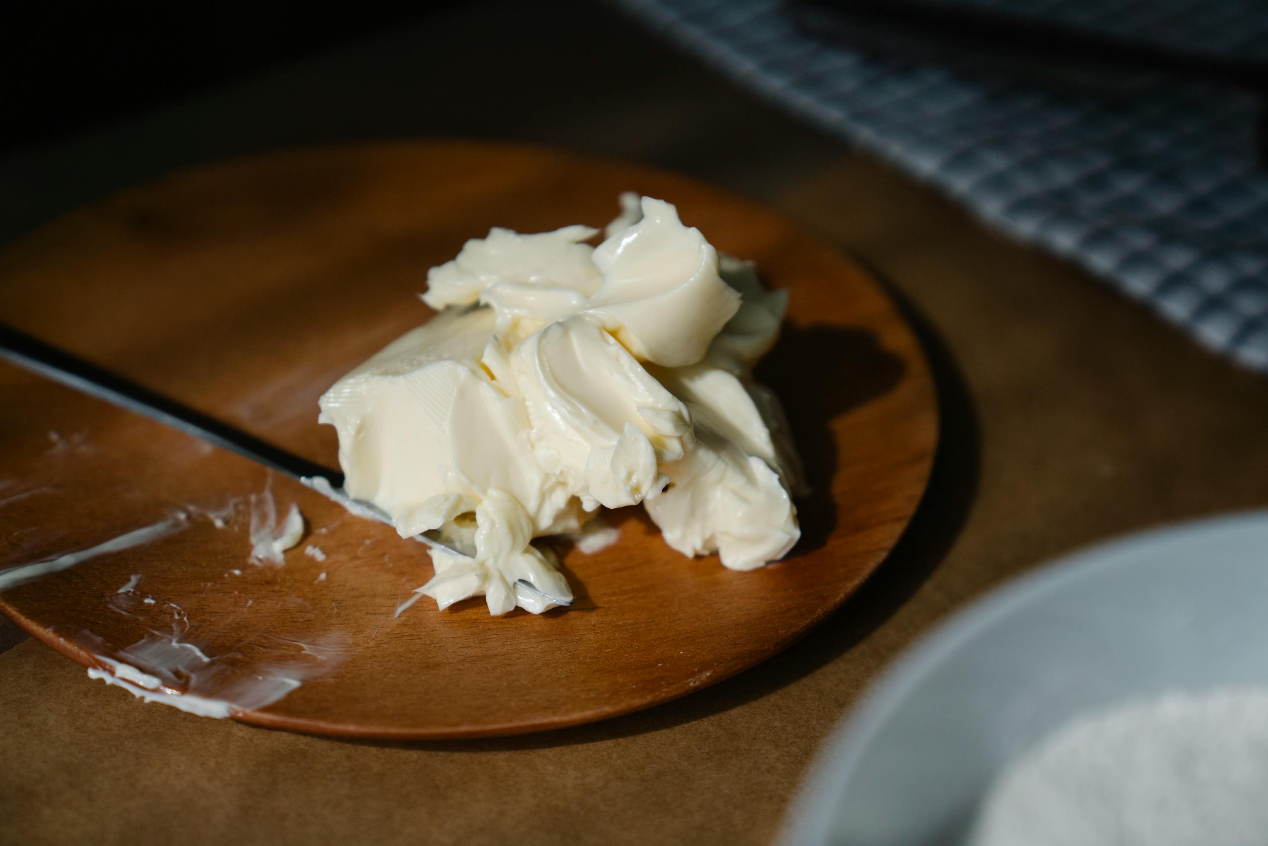 Aesthetic close-up of creamy butter on a wooden plate, perfect for culinary themes.